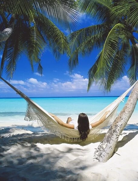 Woman sitting in hammock on beach, Maldives, Indian Ocean, Asia