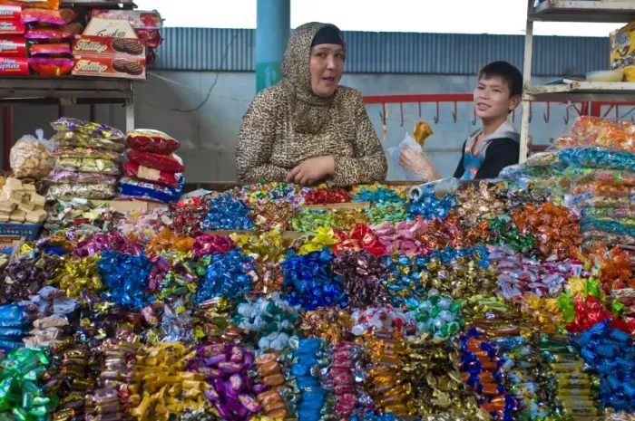 Framed Print : Woman and her son selling sweets on a market stand in the Bazaar of Osh Framed Print : Woman and her son selling sweets on a market stand in the Bazaar of Osh