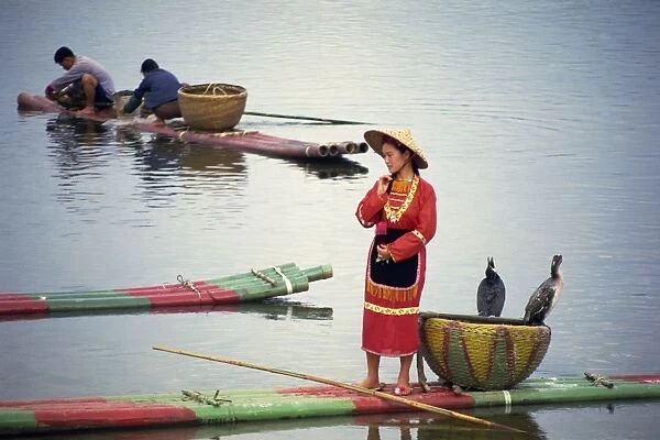 Woman in traditional dress on a raft with cormorants on the Lijiang (River Li) in Guanxi Province