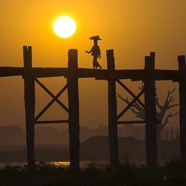Woman on U Bein bridge on Taungthaman lake silhouetted against the sunset