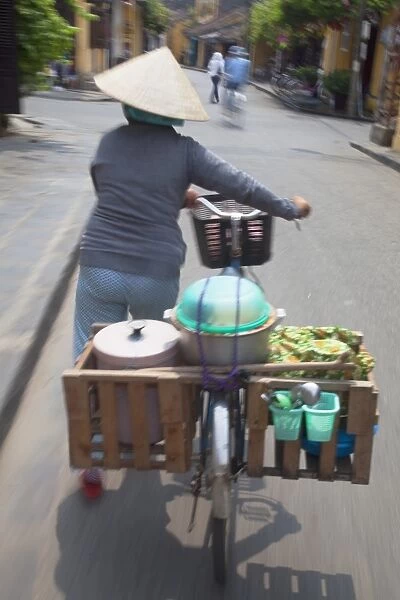 Woman vendor pushing bicycle along street, Hoi An, Quang Nam, Vietnam, Indochina, Southeast Asia, Asia