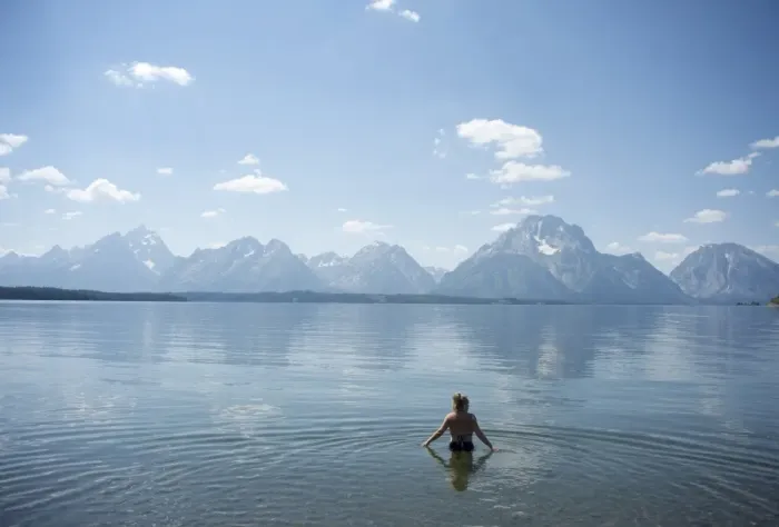 Framed Print : Woman wades in lake with Tetons in distance, Grand Teton National Park Framed Print : Woman wades in lake with Tetons in distance, Grand Teton National Park