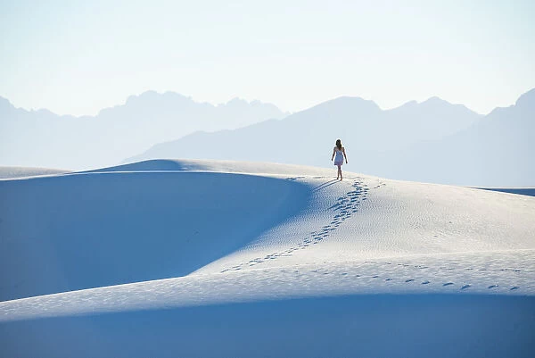 A woman walking along a dunes ridge in White Sands National Park, New Mexico