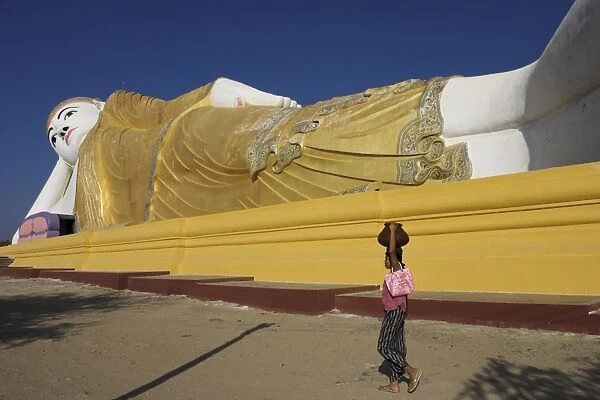 Woman walking past one of the largest reclining Buddha statues in the world