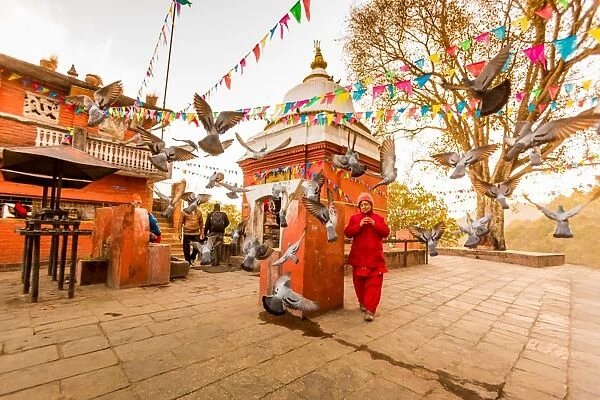 Woman walking and praying with pigeons at the hilltop temple, Bhaktapur, Kathmandu Valley