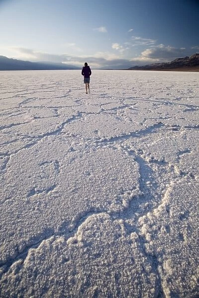 Woman walking on salt flats, Badwater Basin, at minus 282 feet the lowest point in the United States, Death Valley National Park, California, United States of America