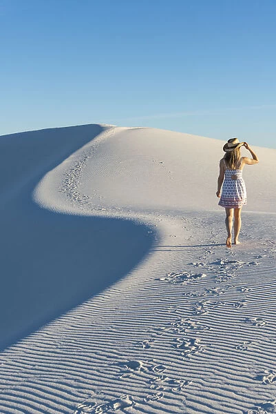 A woman walking along thes curve of a dunes ridge in White Sands National Park