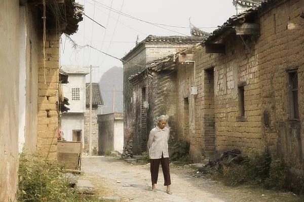 Woman walking through village streets, Yangshuo, Guangxi Province, China, Asia