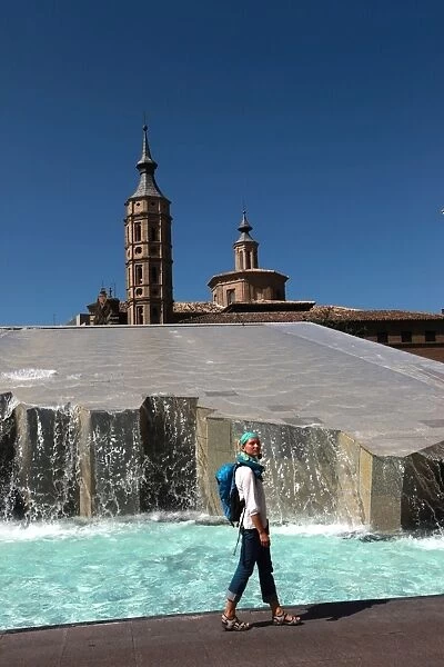 Woman beside water features of Plaza del Pilar, overlooking the Basilica de Nuestra Senora del Pilar, Zaragoza