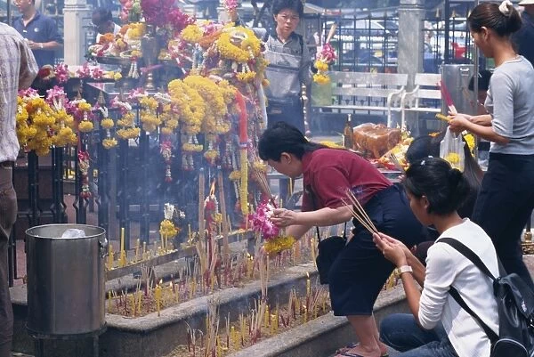 Women with incense sticks worshipping at the Erewan shrine in Bangkok