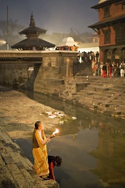 Two women making offerings (puja) before dawn by the Bagmati river