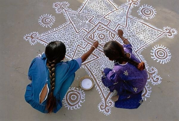 Women painting a Mandana on the ground