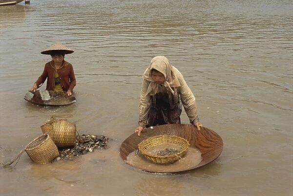 Women panning for gold in the waters of the Mekong River in Vietnam