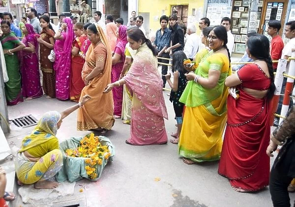Women queueing for Diwali temple puja, buying garlands as offerings for the deity