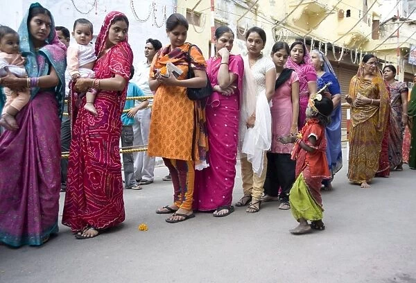 Women queueing for Diwali temple puja, being approached by a child begging for alms