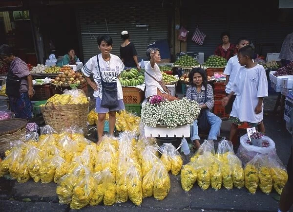 Women selling flowers and fruit from stalls in a street
