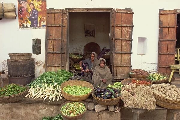 Two women vendors sitting behind at their vegetable
