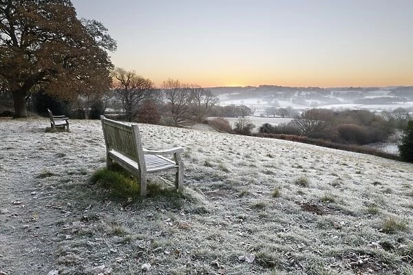 Wooden bench and view over Sussex landscape at sunrise in frost, Burwash, East Sussex