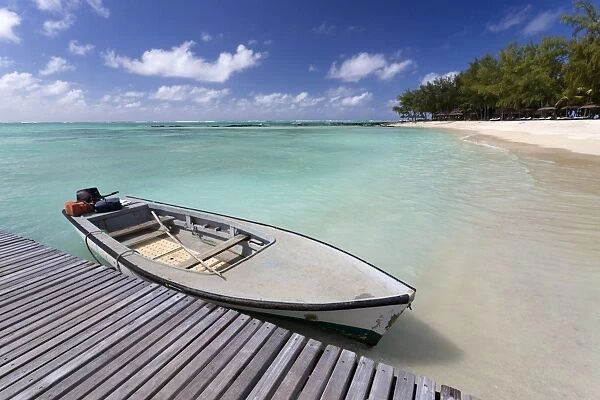 Wooden jetty with a boat tied to it, stretching out into the Indian Ocean off an idyllic beach on Ile Aux Cerfs, Mauritius, Indian Ocean, Africa