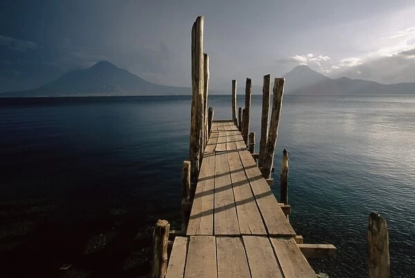 Wooden jetty and volcanoes in the distance