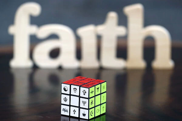 Wooden letters forming the word FAITH and Rubiks cube with religious symbols
