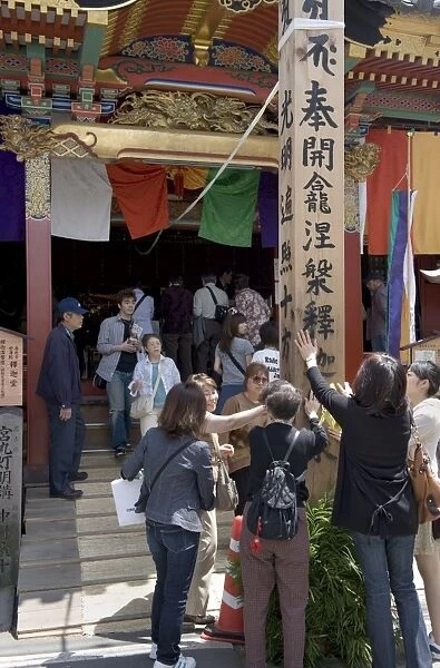 Worshippers touching a wooden obelisk for inspiration at a sub temple of Zenkoji Temple