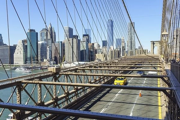 Yellow taxi cab crossing Brooklyn Bridge with the Lower Manhattan skyline behind, New York City, New York, United States of America, North America