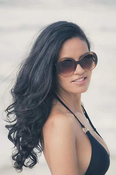Young Brazilian (Latin American) (Latina) woman on the beach in a bikini and sunglasses