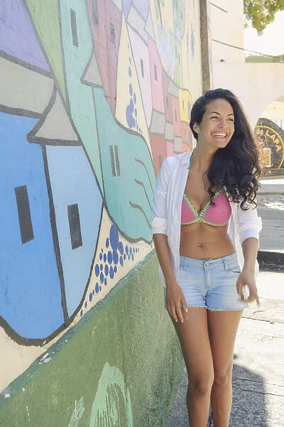 Young Brazilian woman happy and smiling next to a graffiti wall in Lapa, central Rio de Janeiro