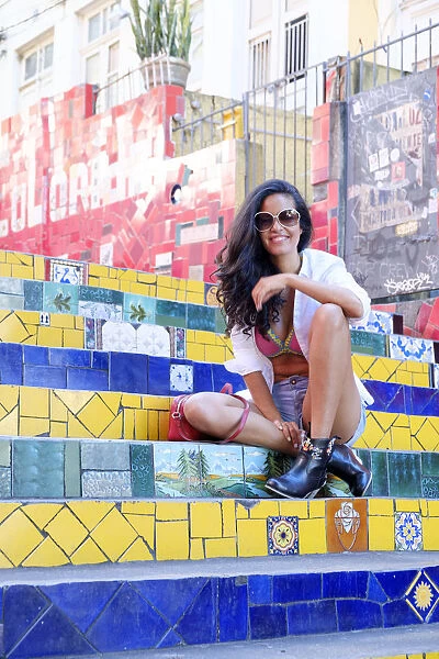Young Brazilian woman in sunglasses sitting on the Selaron steps in Lapa, Rio de Janeiro