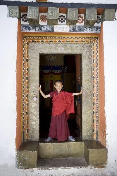 Young Buddhist monk in doorway, Paro Dzong, Paro, Bhutan, Asia
