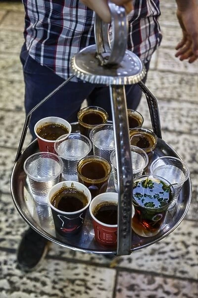 Young man holding a tray with coffee, tea and water in old city, Jerusalem, Israel
