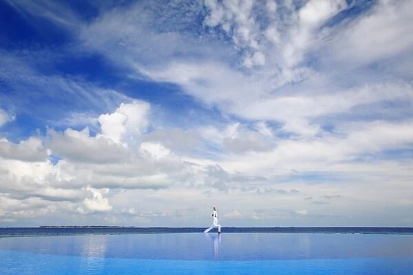 Young man meditating by infinity pool, Maldives, Indian Ocean, Asia