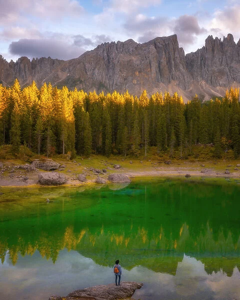 Young man observing the beauty of Lago Di Carezza at sunset, Dolomites, Italy, Europe