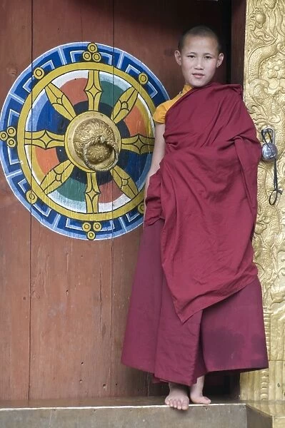 Young monk standing in the door of the Chimi Lhakhang monastery, Bhutan, Asia