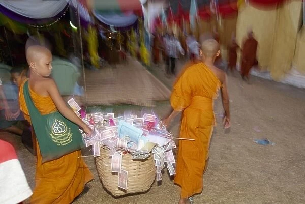 Two young monks carrying basket of donations during