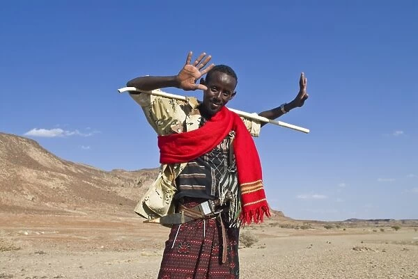 A young native man grinnig cheekily and holding a stick, Lac Abbe, Djibouti, Africa
