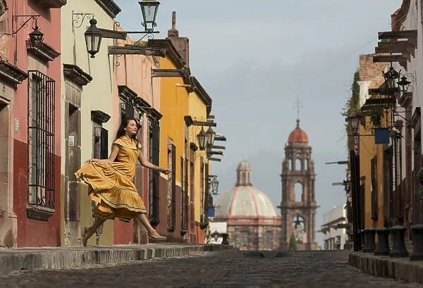 Young woman dancing down cobbled street (recreo), San Miguel de Allende, Guanajuato, Mexico, North America