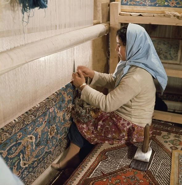 Young woman weaving carpet on loom