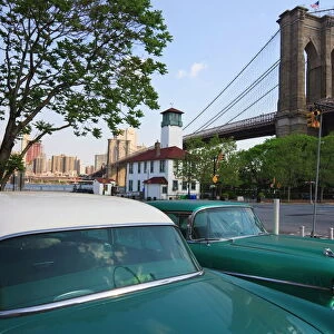 Two 1950s cars parked near the Brooklyn Bridge at Fulton Ferry Landing