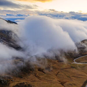 Aerial view by drone of fog over scenic road crossing Giau Pass in a sea of clouds at