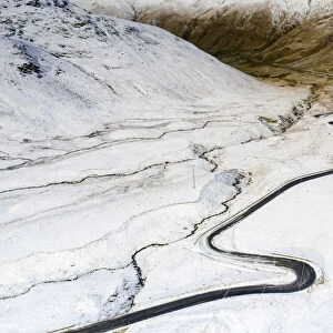 Aerial view by drone of S-shape road towards Stelvio Pass in the snowy landscape, Bormio