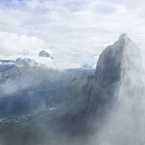 Aerial view of fog over the majestic Segla Mountain peak emerging from clouds
