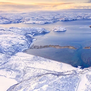Aerial view of Norwegian County Road 98 along snowy mountains above Laksefjorden, Lebesby