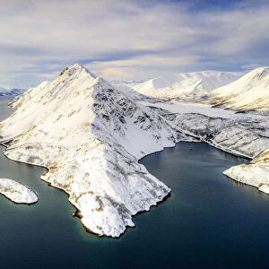 Aerial view of snow capped mountains along the clear water of Altafjord