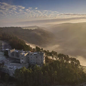 Aerial vista of Castle Drogo and the Teign Valley in morning mist in winter, Dartmoor