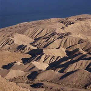 Arid hills on shore of Dead Sea, with Jordanian Mountains in the background