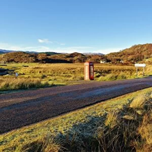An autumn view of a red telephone box at the side of a quiet road in the remote Ardnamurchan