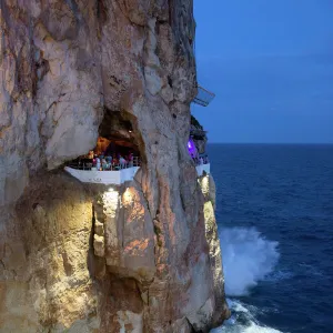 Bar built in cliff caves, Cova d en Xoroi in evening, Cala en Porter, Menorca, Balearic Islands