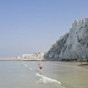 A beach under the chalk cliffs, mother and child paddling, Nuclear Power Station in the background